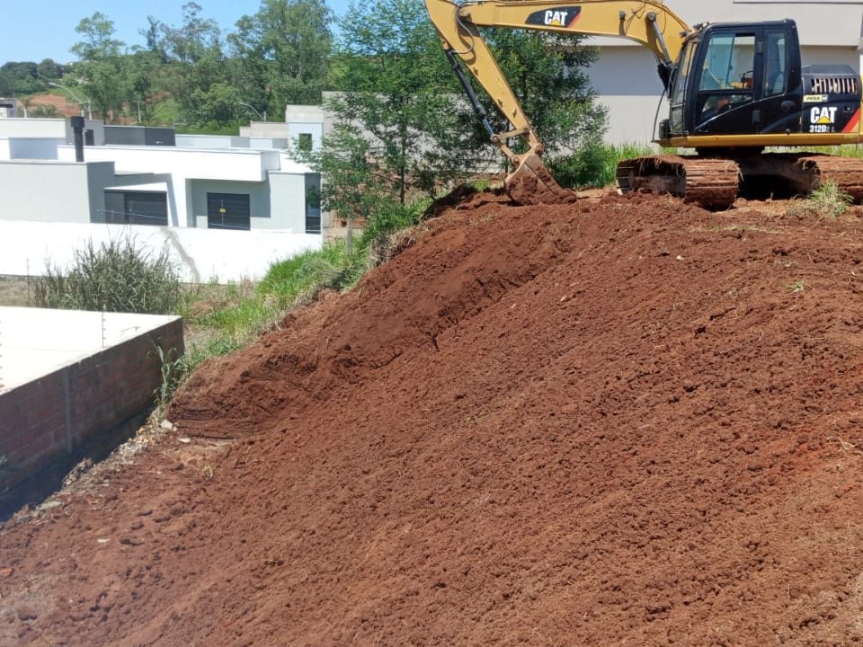 Escavadeira CAT fazendo corte de barranco em lote residencial
