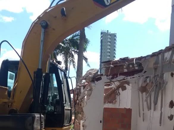 Escavadeira CAT demolindo construção antiga